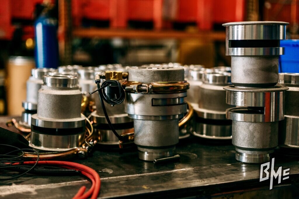 Spray valve bodies and components staged on a bench for assembly