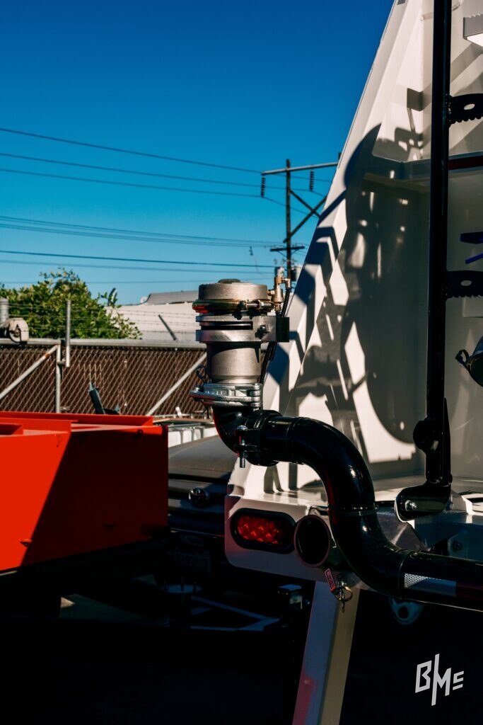 Spray valve mounted on a water truck outdoors against a blue sky